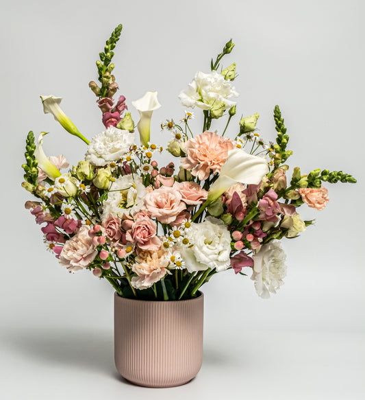 Blush and white floral arrangement with calla lilies, roses, and carnations in a matte blush ceramic vase – handcrafted romantic design by Rainbow Floral Toronto.