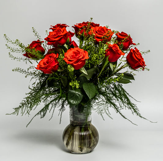 Classic red rose vase arrangement with lush greenery in a smoked glass vase – handcrafted romantic floral design by Rainbow Floral Toronto.