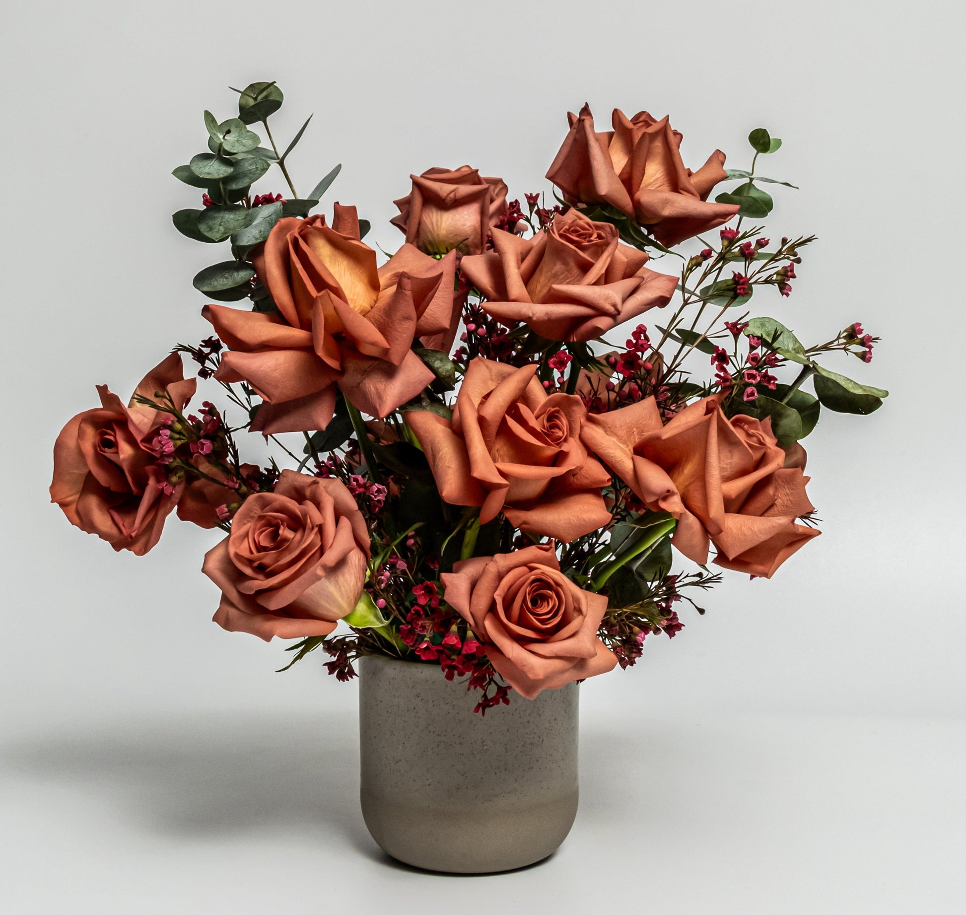 Terracotta rose and red accent flower arrangement with eucalyptus in a matte stone vase – handcrafted modern design by Rainbow Floral Toronto.